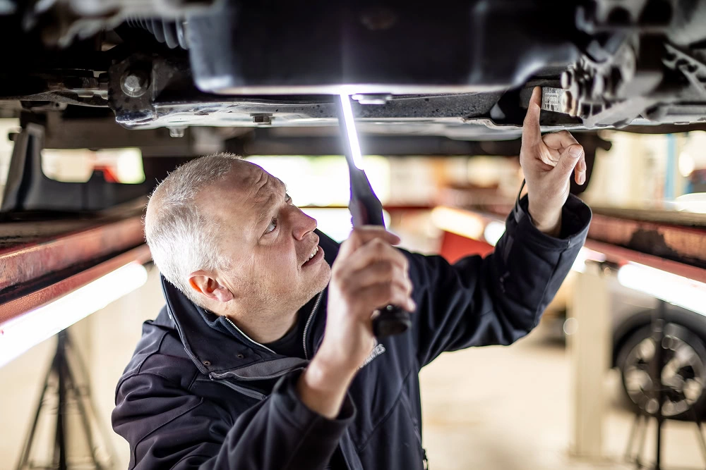 Automonteur van Best Autotaxaties die inspectie uitvoert aan de onderkant van een van de auto's